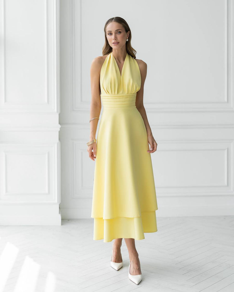 Woman wearing a yellow dress against a white wall